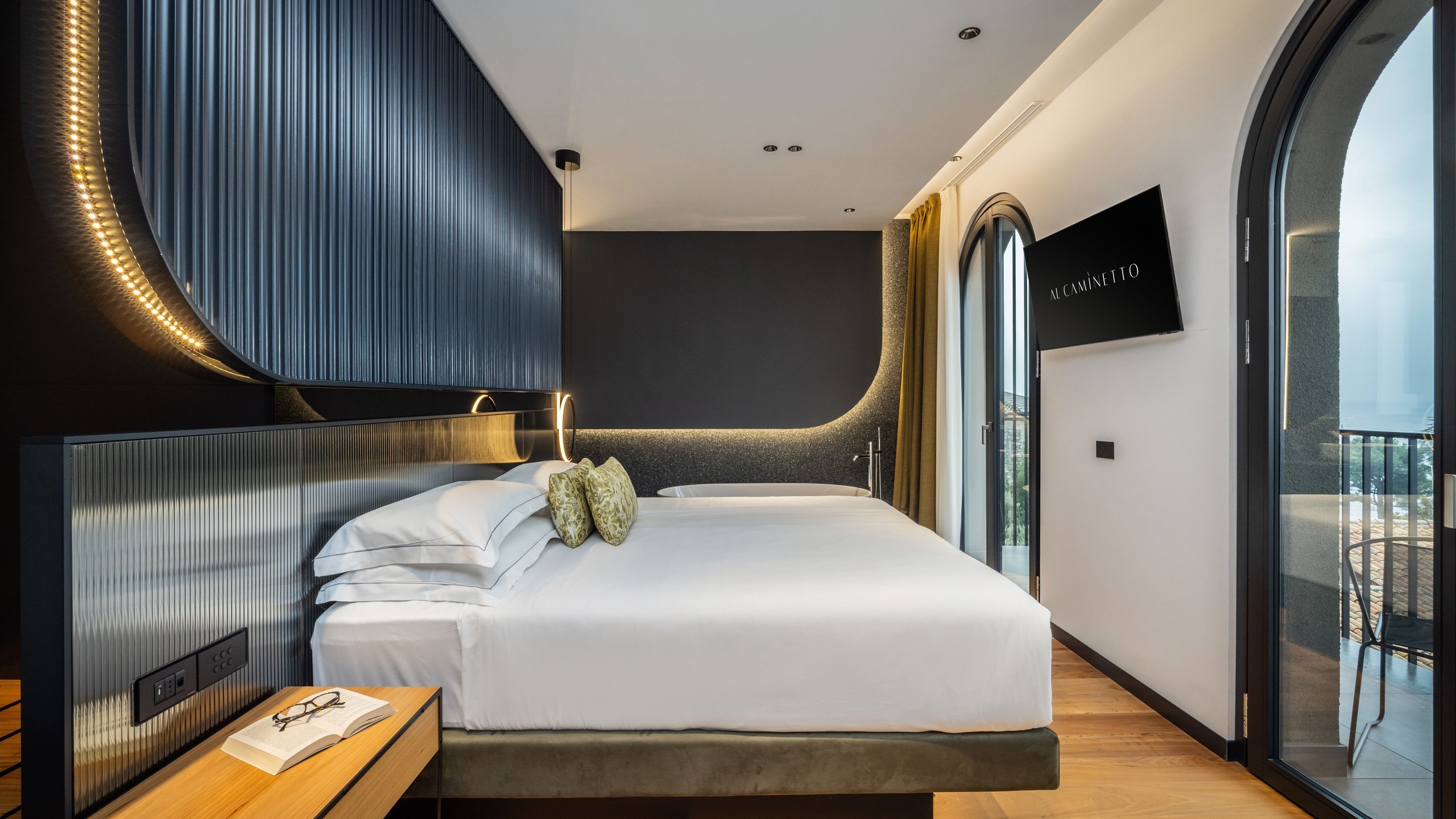 Attraverso le grandi vetrate, la luce e i colori del Lago di Garda si riflettono in un’atmosfera senza tempo. Tocchi di blu e verde, un’eleganza discreta votata al comfort, e una vasca da bagno freestanding.