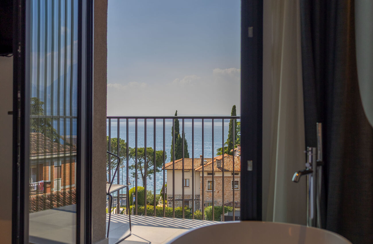 Suite vista lago | Attraverso le grandi vetrate, la luce e i colori del Lago di Garda si riflettono in un’atmosfera senza tempo. Tocchi di blu e verde, un’eleganza discreta votata al comfort, e una vasca da bagno freestanding.