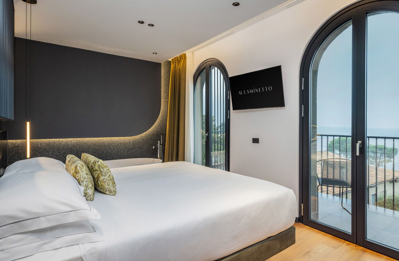 Suite vista lago | Attraverso le grandi vetrate, la luce e i colori del Lago di Garda si riflettono in un’atmosfera senza tempo. Tocchi di blu e verde, un’eleganza discreta votata al comfort, e una vasca da bagno freestanding.