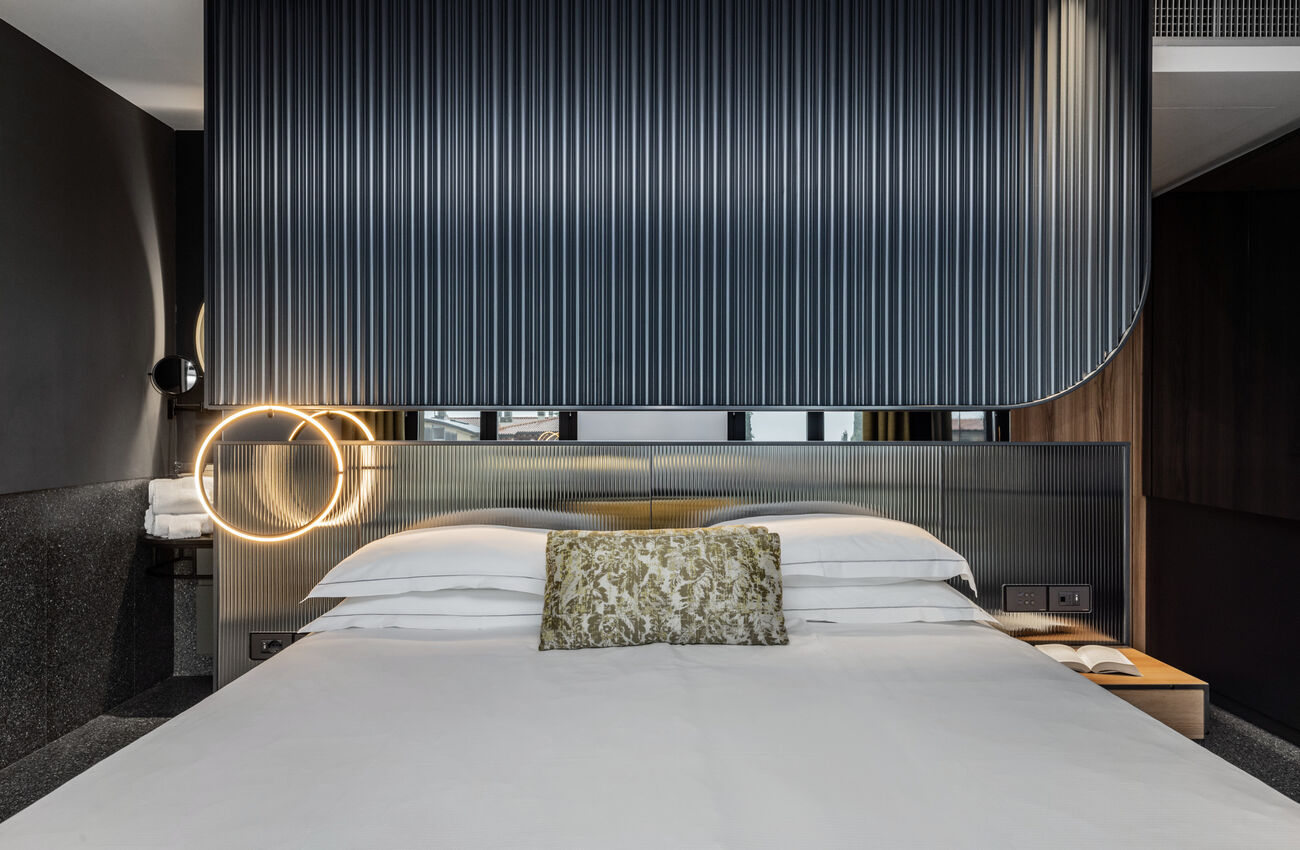 Junior suite vista lago | La luce del lago attraversa lo spazio e ne rivela le geometrie, in un gioco tra materia, colori e profondità. La doccia walk-in completa l’ambiente come un gesto naturale. 
