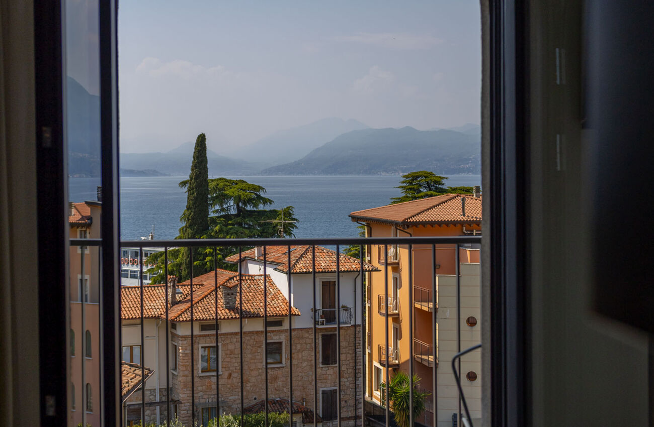 Junior suite vista lago | La luce del lago attraversa lo spazio e ne rivela le geometrie, in un gioco tra materia, colori e profondità. La doccia walk-in completa l’ambiente come un gesto naturale. 