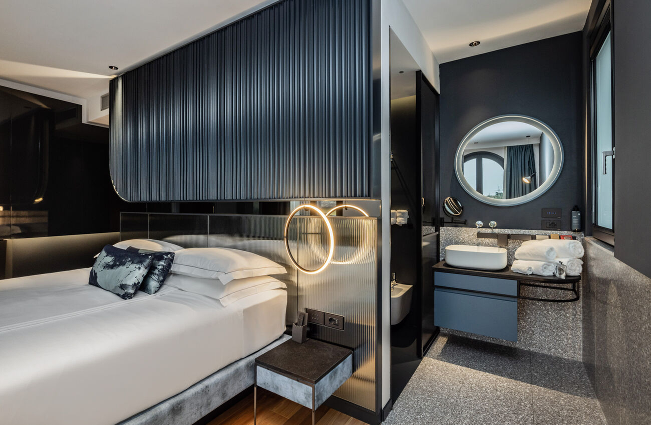 Junior suite vista lago laterale | Un’atmosfera che nasce dall’incontro di volumi e proporzioni, pensati per convivere in equilibrio e continuità. Presenza naturale, la doccia walk-in fluisce nello spazio senza forzature. 
